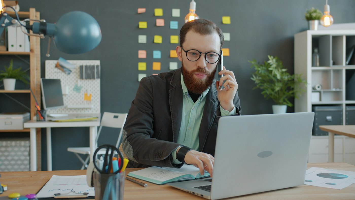 Accountant on the phone in the office using a laptop