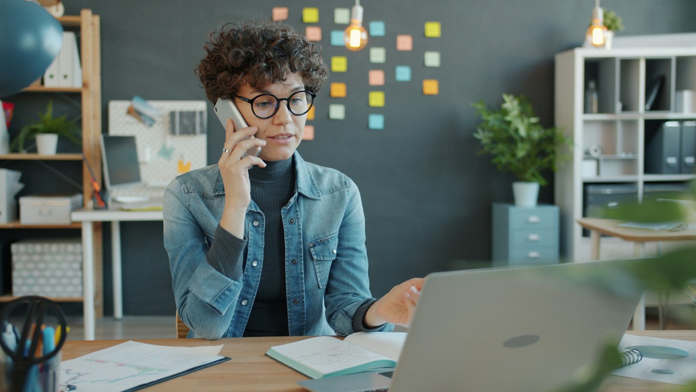 Office worker on the phone while checking emails on a laptop